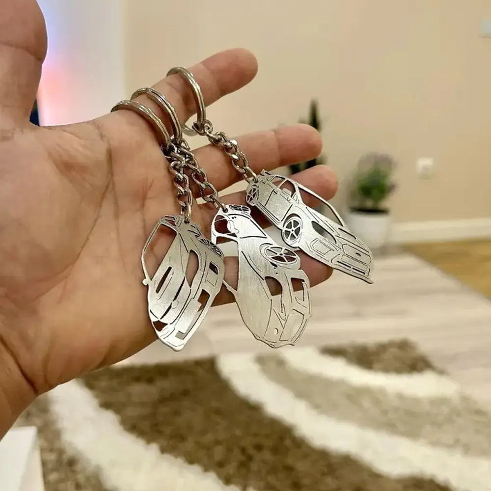 Customized car model metal keychain featuring silver metallic car-shaped designs with intricate cut-out details attached to a chain and ring.