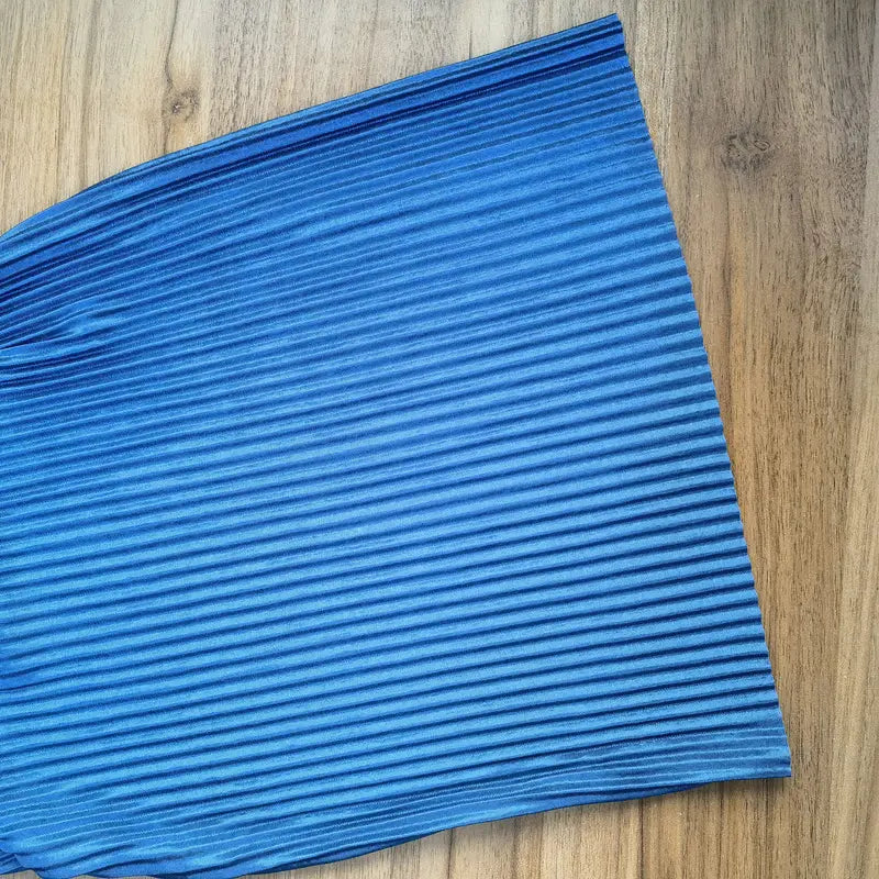 Eine lebhaft blaue, weit geschnittene, plissierte Sommerhose für Damen mit elastischem Bund und glattem, leicht glänzendem Stoff.