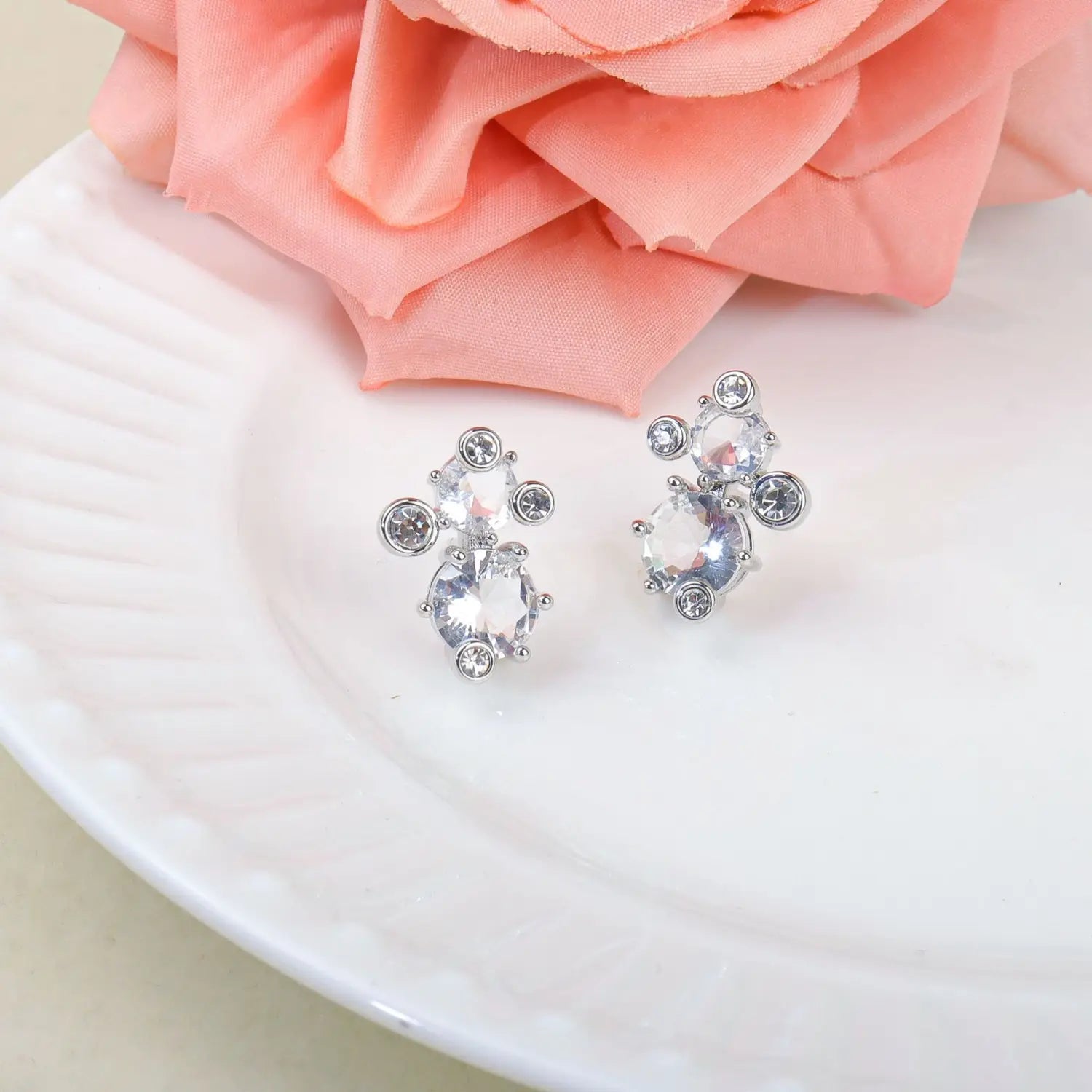 Boucles d’oreilles à tige argentées avec un design en grappe, comprenant des cristaux facettés transparents et des pierres d’accent plus petites, issues d’un ensemble de bijoux de mariage en cristal incluant un collier en argent et des boucles d’oreilles.