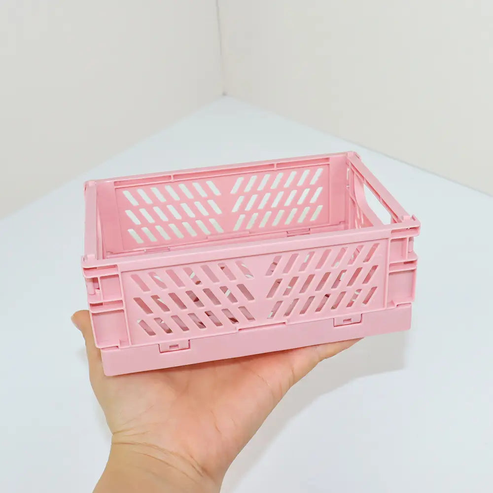 eine rosafarbene Kunststoff-Falt-Aufbewahrungsbox mit Rautenmuster und ineinandergreifenden Seitenpaneelen, ausgelegt als pastellfarbener Kunststoff-Desktop-Organizer, Aufbewahrungsboxen-Körbchen