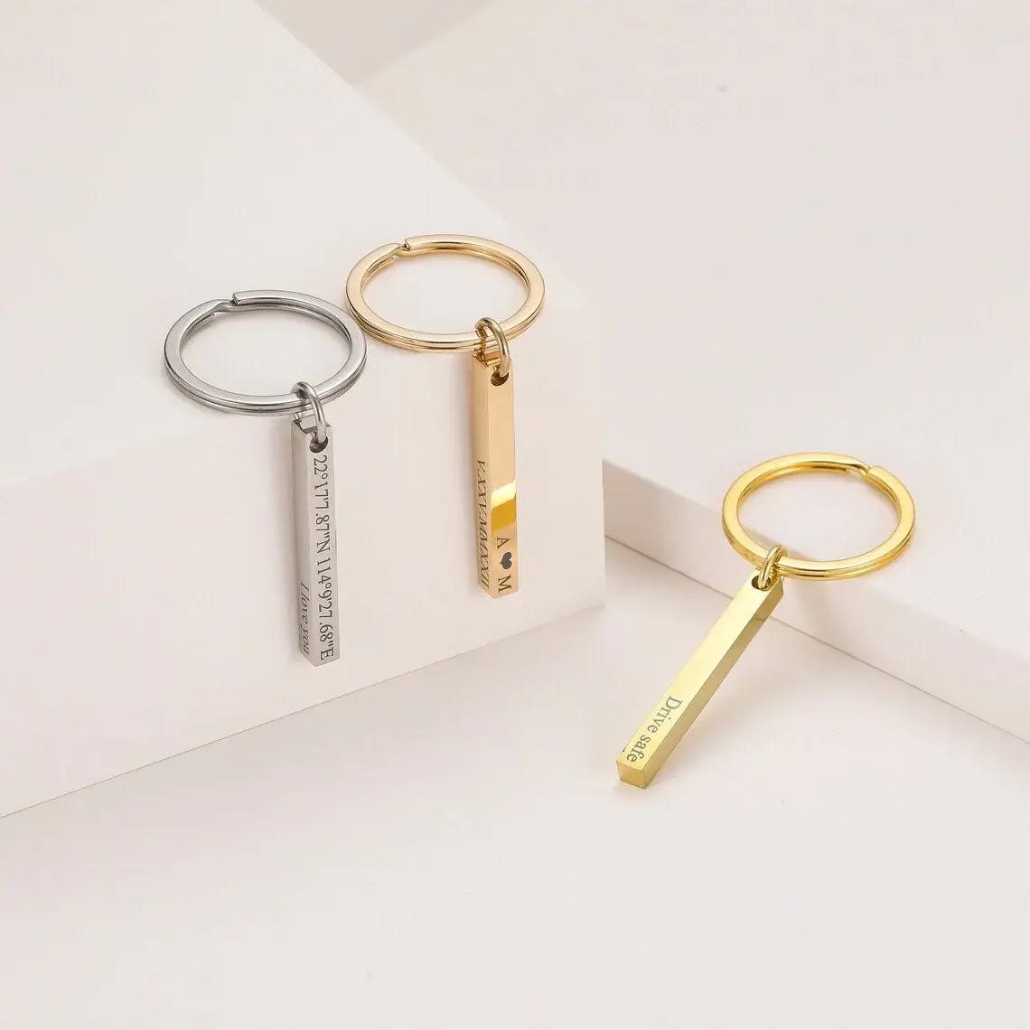 Silver and gold-toned stainless steel rectangular bar keychains with custom engraved text featuring a minimalist design.