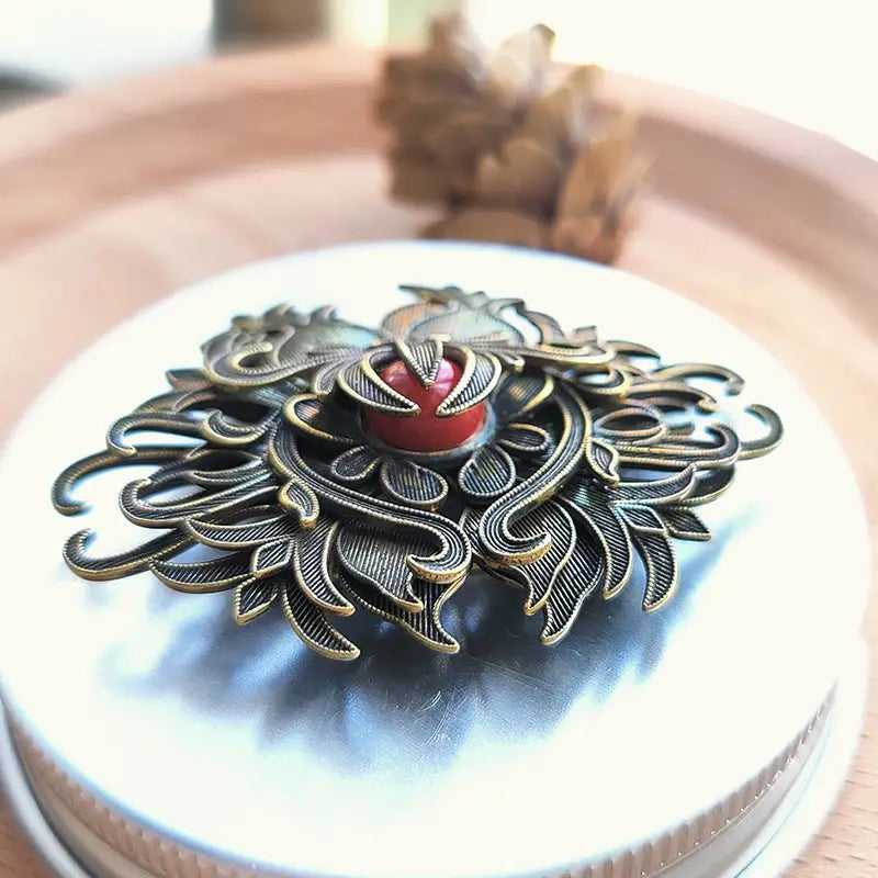 antique brass filigree brooch featuring a floral design with a central red gemstone suitable for palace jewelry collections.
