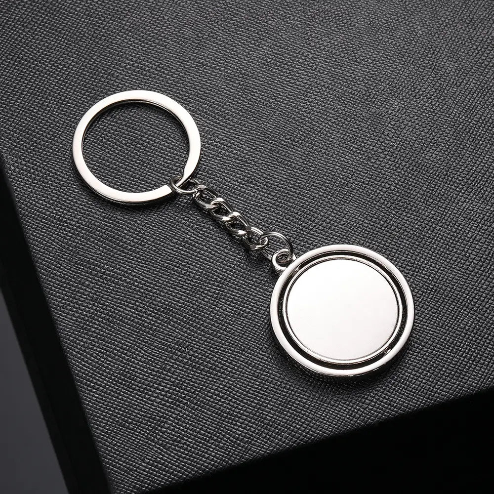 Silver metallic rotating circle keychain gift featuring a double-sided circular disc attached by a short chain.
