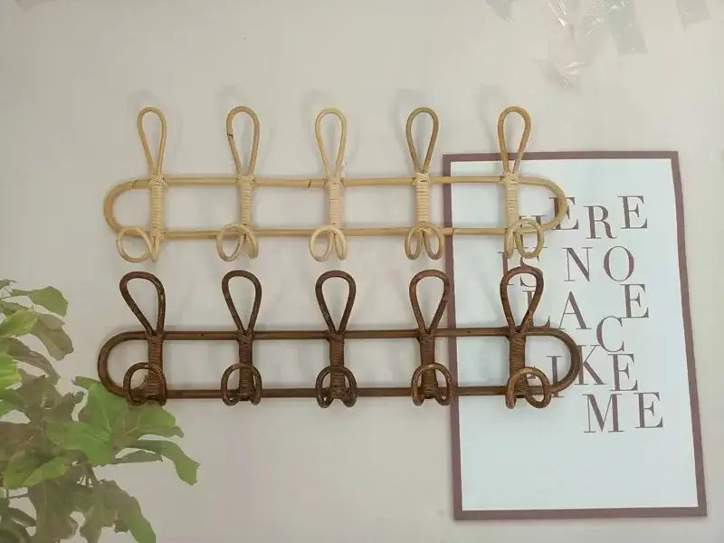Rattan-Kinder-Wandhaken zur Aufbewahrung von Kleidung mit an der Wand montiertem Garderobenhalter mit zwei Reihen von Haken in hellbeigen Naturtönen und dunkelbraunen Farben.