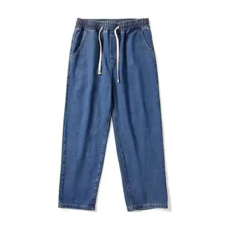 Pantalon de survêtement en denim bleu avec taille élastique et cordons blancs, présenté dans la collection de jeans en denim ample à jambes larges, à broderie croisée.