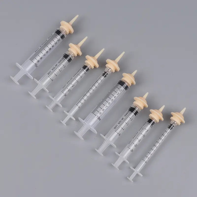 Set of clear plastic pet oral syringes with beige rubber plungers black measurement markings and silicone nipples for feeding.