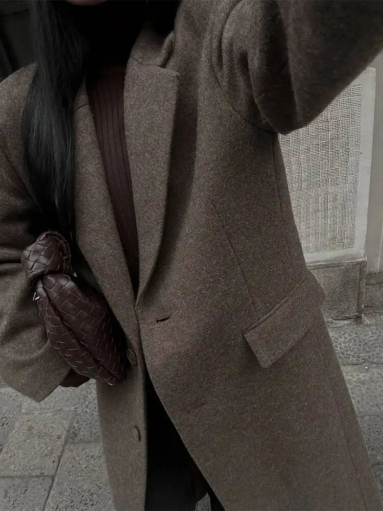 A brown woven leather crossbody bag with a distinctive knot design paired with a brown wool blend overcoat women winter commuter jacket.