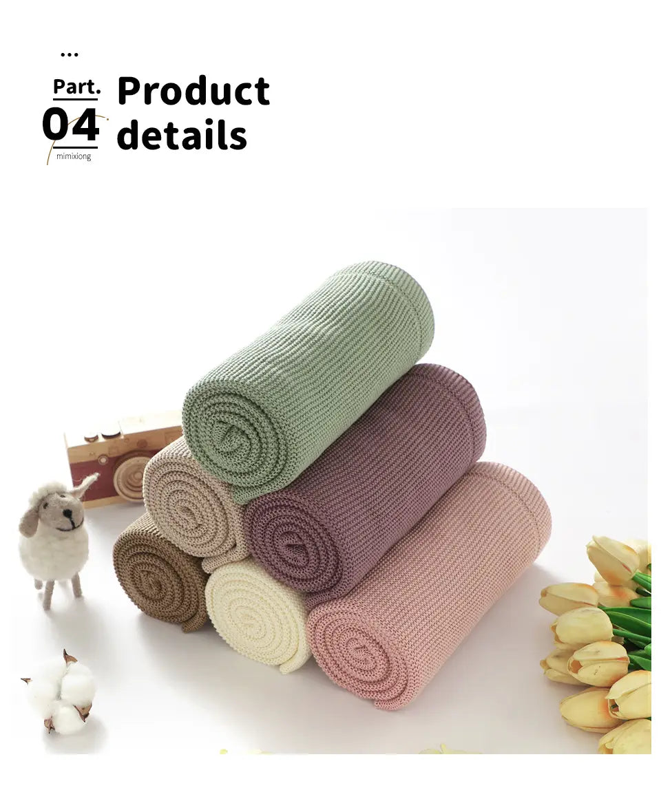 Ein Stapel weicher gerippter Strickschals in Pastelltönen, einschließlich Blassrosa, aus Baumwolle gefertigt, dargestellt als Wickelunterlage und Babydecke.