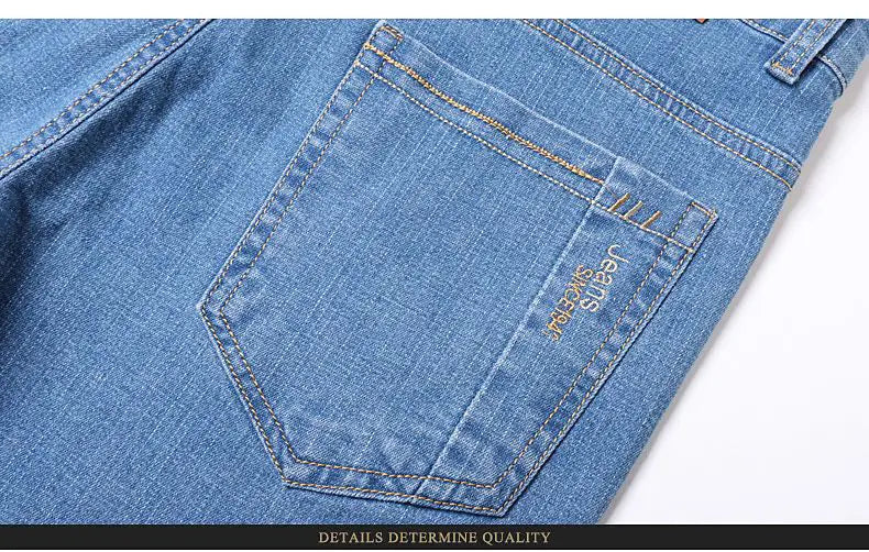 men’s blue stretch cotton straight jeans casual trousers showing the back pocket with gold-colored stitching and a small embroidered brand tag