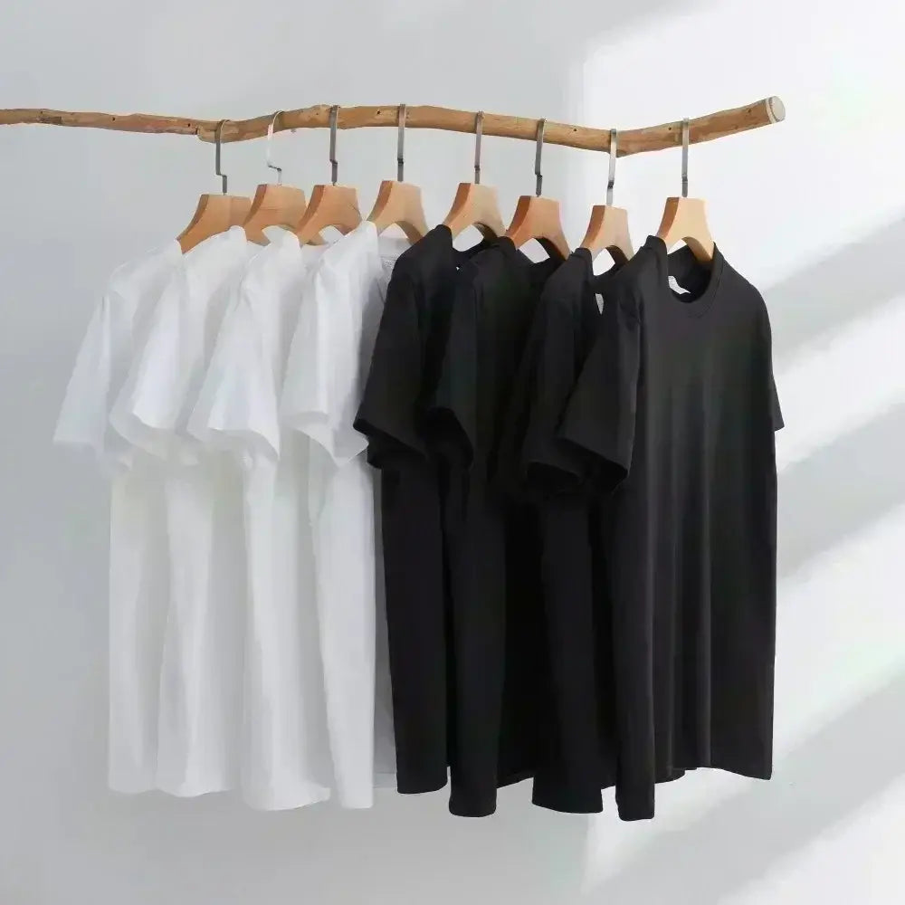 A minimalist black and white cotton funny quote novelty graphic tee shirt collection hanging neatly on wooden hangers.