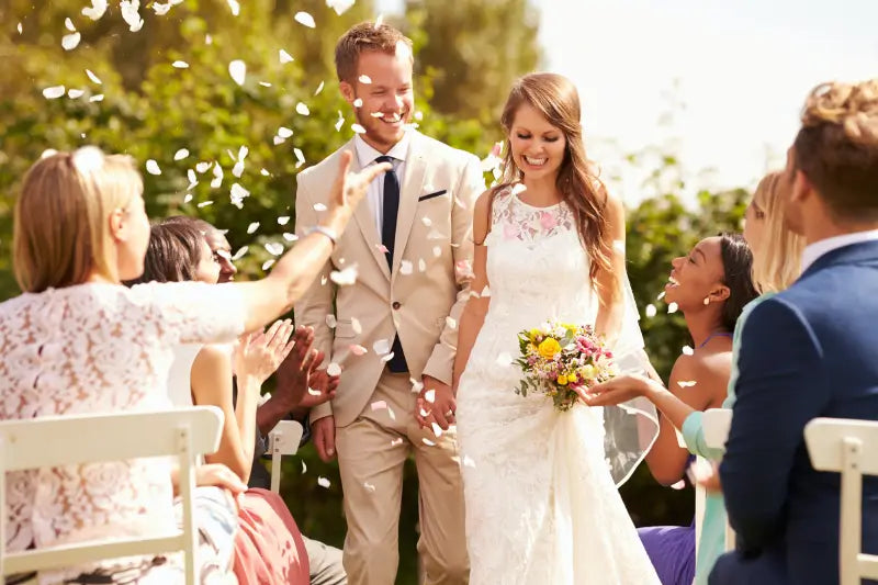 white lace wedding dress with floral embroidery and a fitted bodice paired with a white silk rose wedding bouquet with lace and pearls for bridal use