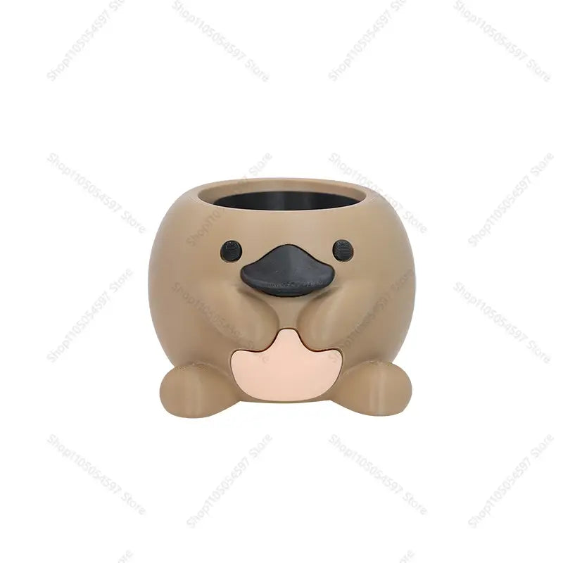 Encantadora maceta de cerámica color beige con forma de ornitorrinco, con ojos y pico negros y un parche de panza rosa, diseñada como maceta de plástico para escritorio para suculentas.