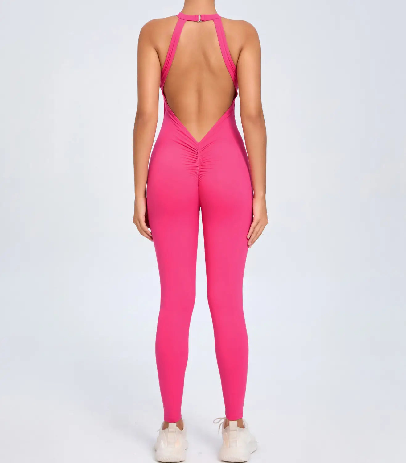 A vibrant fuchsia one-piece athletic jumpsuit with a halter neck and open back design shown from the back side for workout and activewear use.