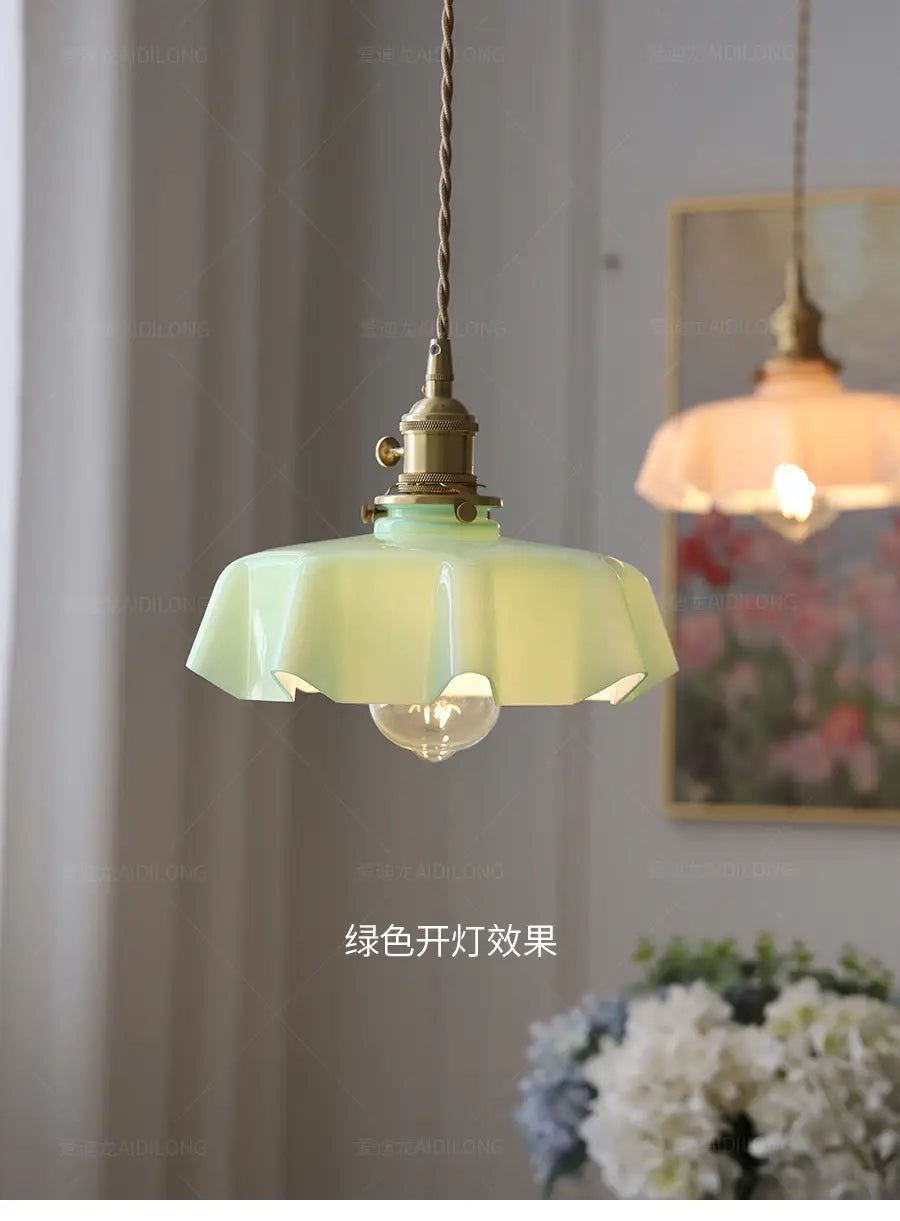 Un luminaire délicat suspendu à jupe florale en verre vert menthe avec un abat-jour cannelé à aspect de pétales et une tête de lampe en cuivre montrée depuis l’avant.