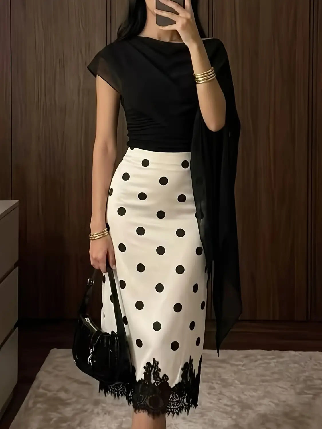 Falda midi de lunares blanco y negro con ribete de encaje que presenta un patrón clásico y detalles elegantes.
