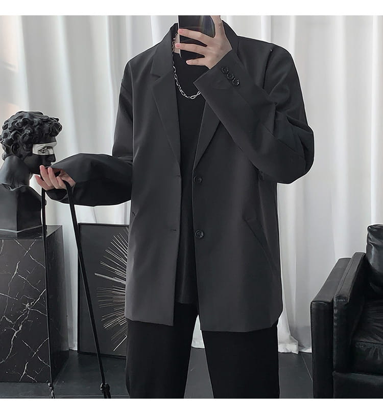 Schwarze übergroße Blazerjacke für Herren mit schlichter modernem Schnitt und dezenten Knopfdetails, ideal für den Freizeitgebrauch.
