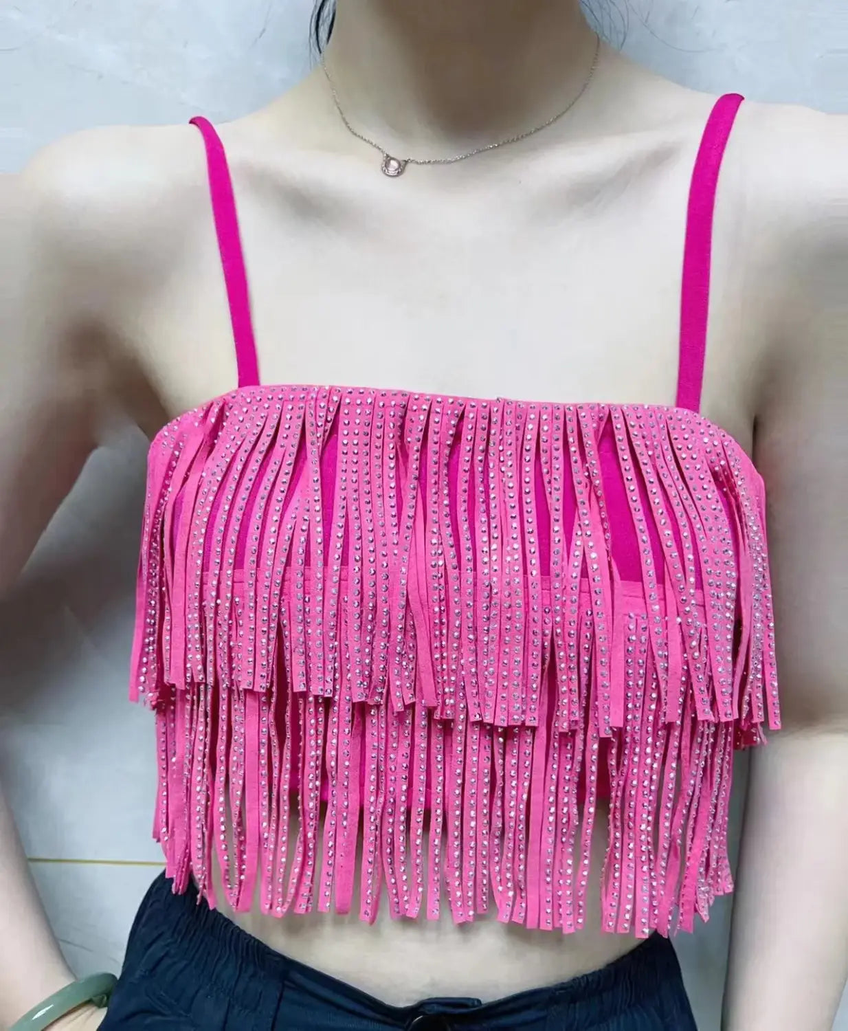 Haut court rose vif à franges, avec fines bretelles et des strass scintillants intégrés le long des franges, assorti à une mini-jupe taille haute à franges en strass.