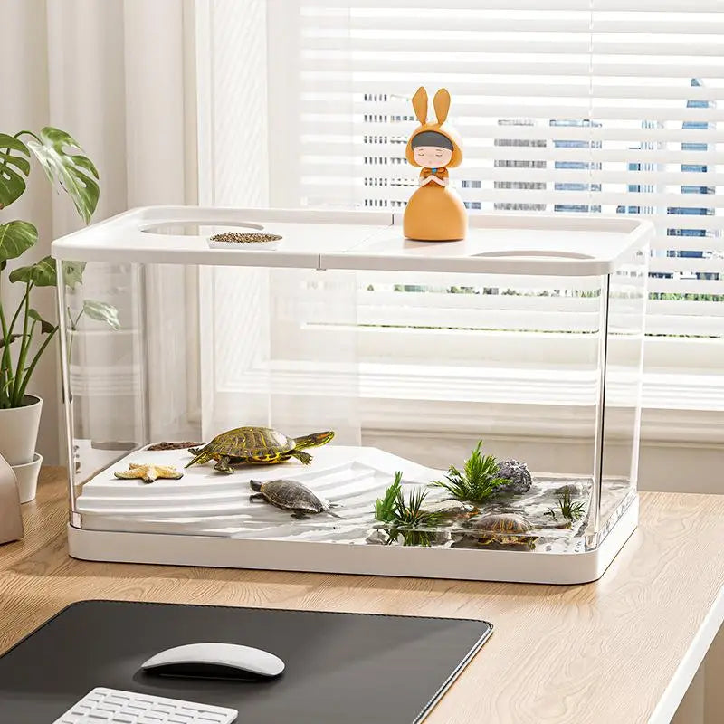White rectangular ecological desktop fish tank with clear glass sides and a white plastic top featuring two circular food wells housing several small turtles and aquatic plants in shallow water.