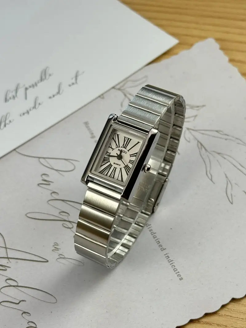 Vintage gold rectangular quartz watch for women featuring a silver rectangular case with a sleek metallic band and roman numeral dial.