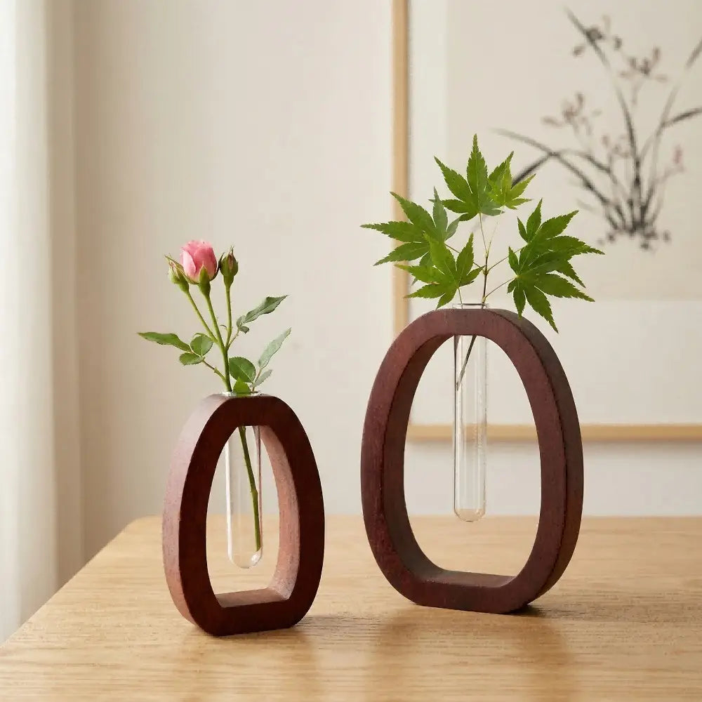 Two minimalist wooden oval vases each holding a clear glass test tube with fresh greenery in a wooden hydroponic glass tube vase desktop planter.