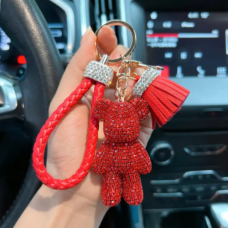 Red braided leather keychain featuring a sparkling rhinestone-covered teddy bear charm with a matching red tassel and silver-toned hardware.