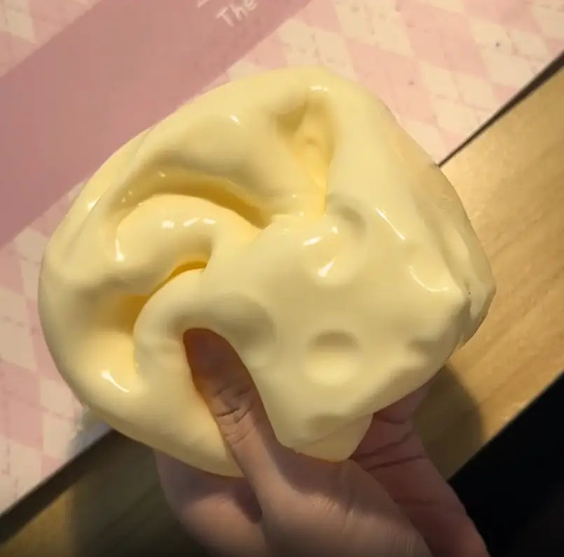 un jouet à mâcher et à malaxer en forme de fromage jaune pâle, brillant, conçu pour soulager le stress, de texture souple et molle, conçu pour apaiser le stress lié au jouet.