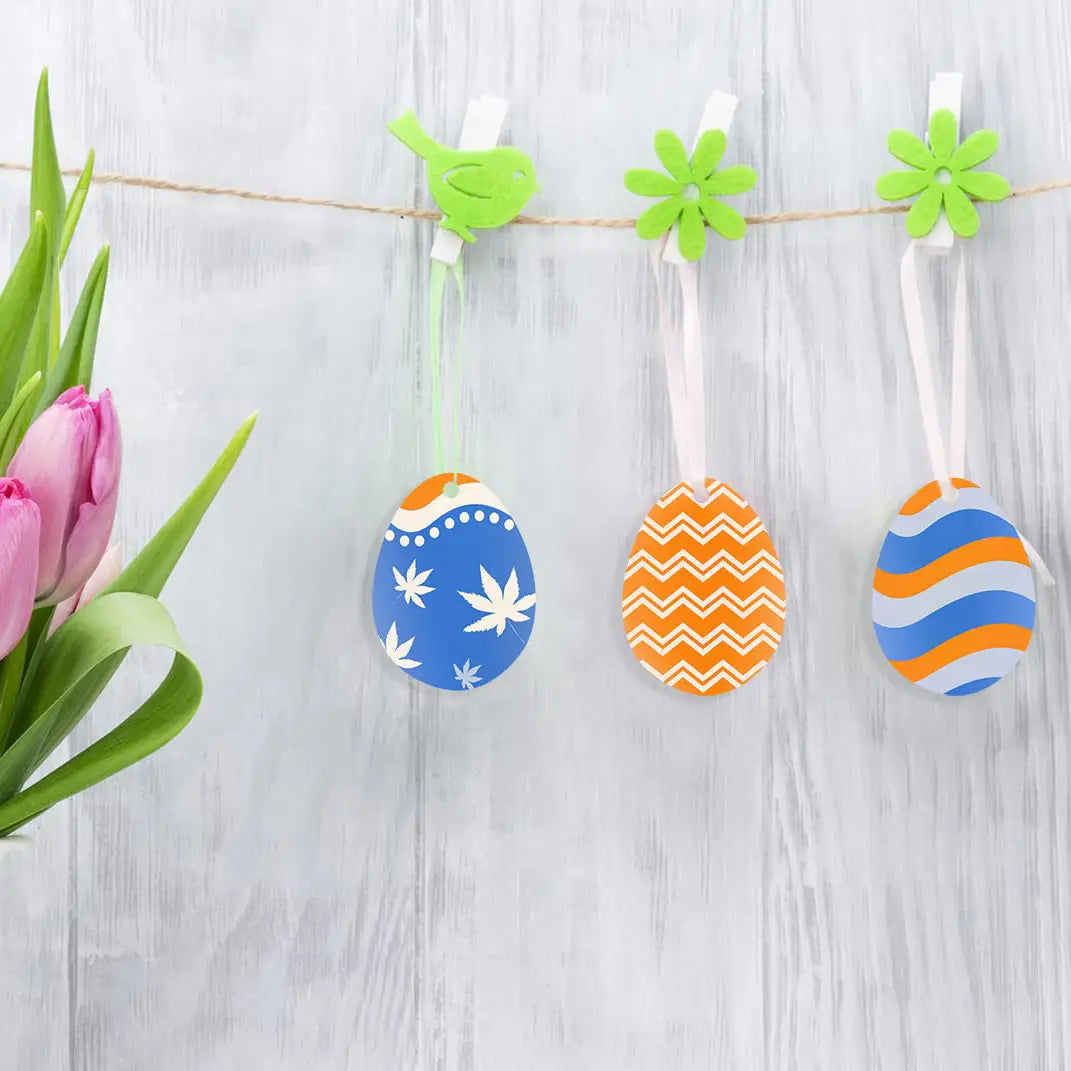 Trois ornements vierges en acrylique pour œufs de Pâques à motifs colorés, suspendus à une ficelle avec des pinces de maintien vertes, en lot de 30 ou 50 pièces.