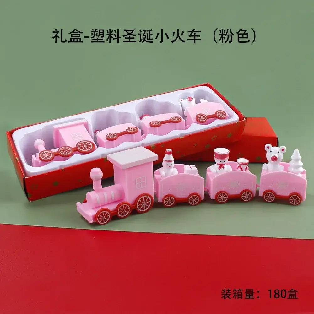 Décoration de table de fêtes de Noël en bois en forme de train, comportant un ensemble de jouets de train en plastique rose avec des roues rouges et de petites figurines dans chaque wagon.