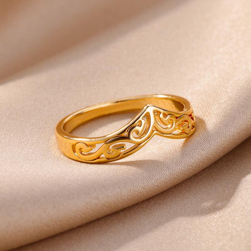 A delicate gold color stainless steel ring for women featuring an intricate swirling filigree design with a small red accent stone suitable for vintage wedding jewelry.