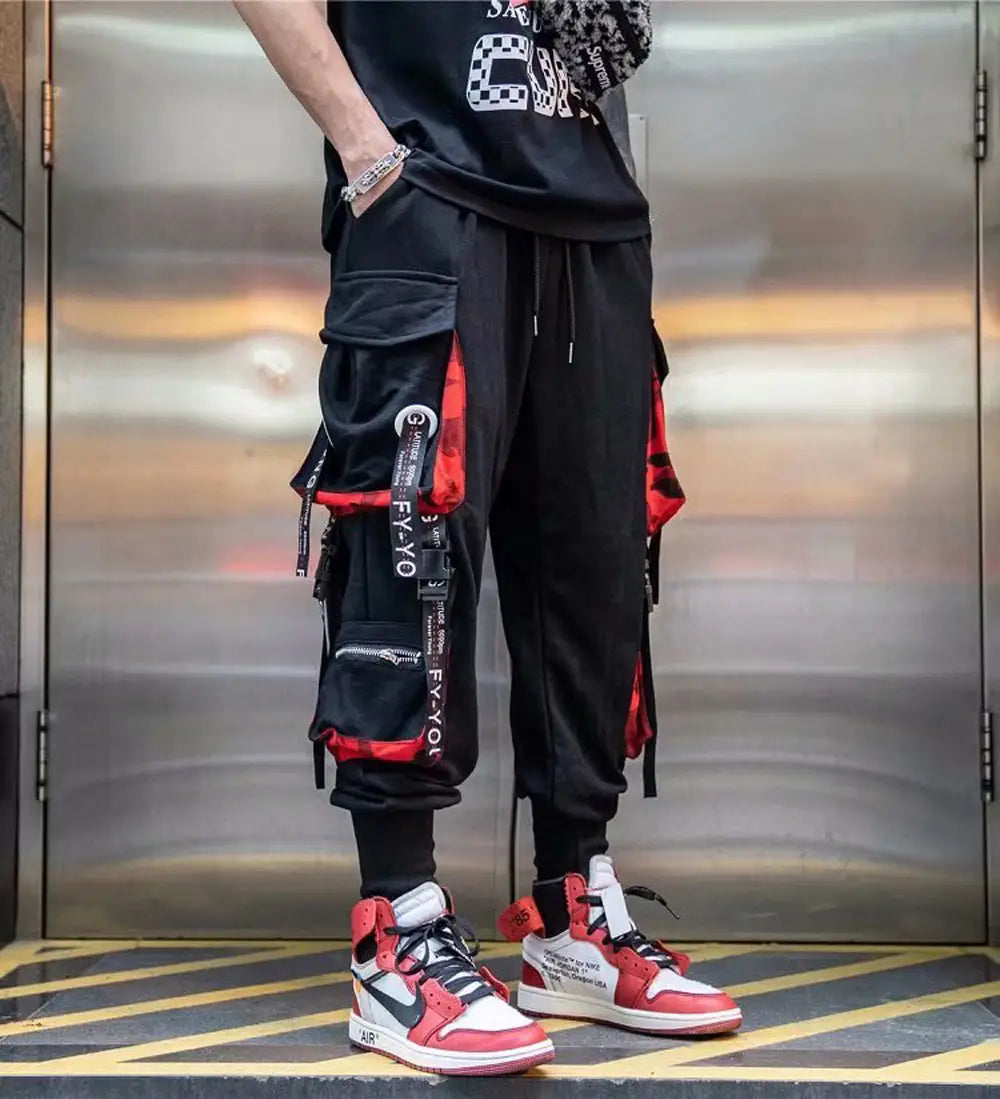 Pantalon cargo joggers streetwear pour hommes en noir, avec des accents rouges ; plusieurs poches et une ceinture à cordon de serrage, conçus pour le confort et la fonctionnalité.