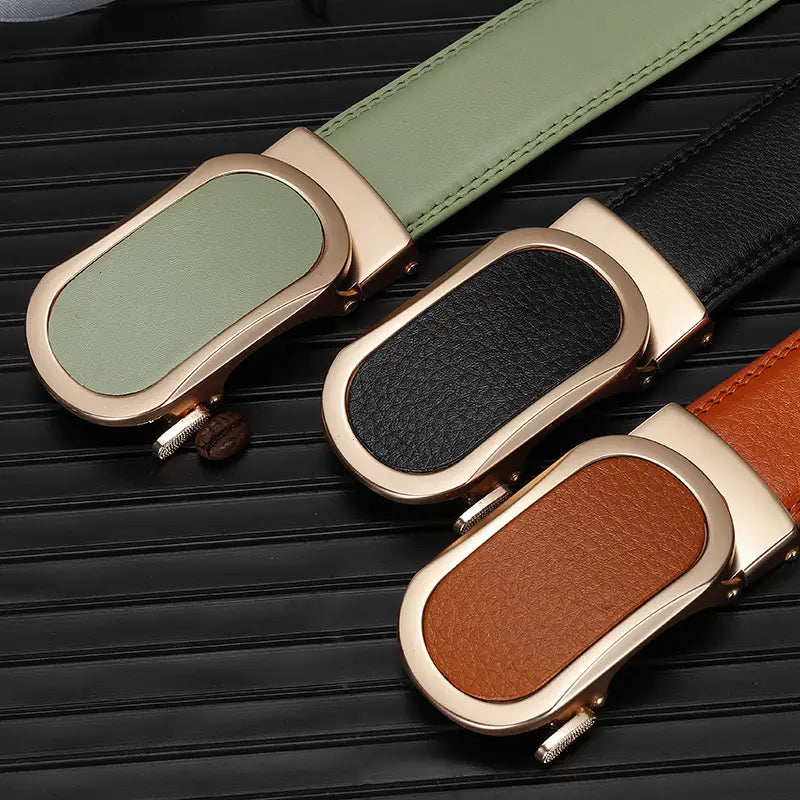 Tres cinturones de cuero con correas en verde oliva, negro y marrón, con hebillas automáticas de tono dorado rosado para hombres informales.