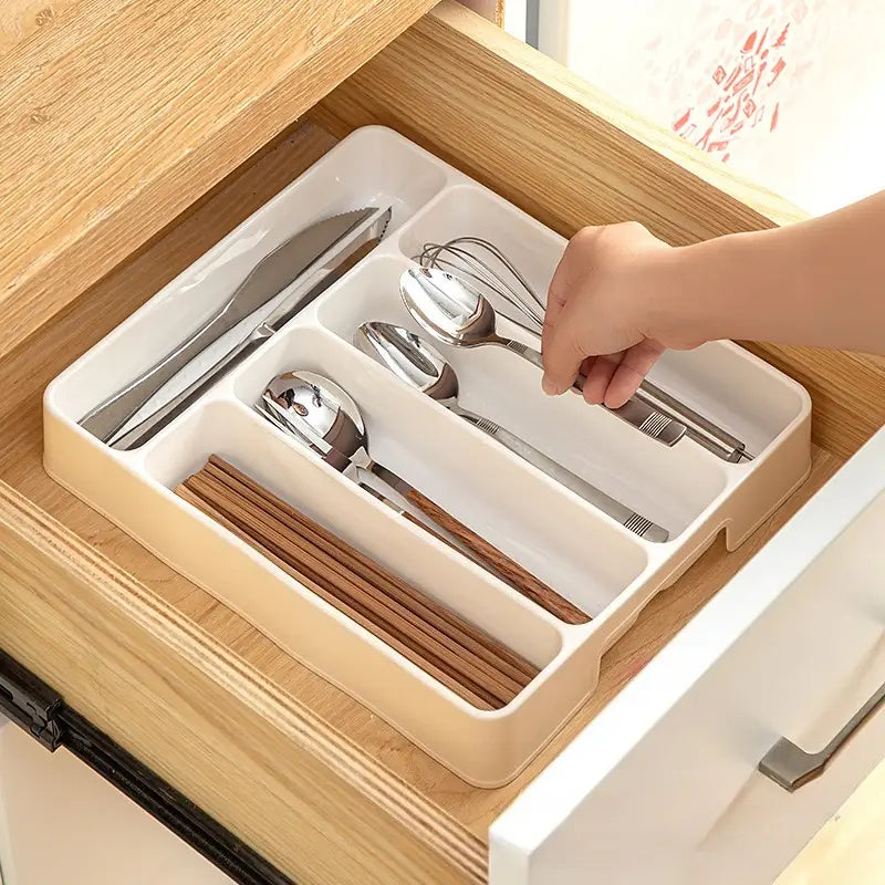 Bac d’organisation réglable pour ustensiles de cuisine en plastique beige, pour tiroir, avec compartiments segmentés accueillant des couverts et des baguettes en bois.