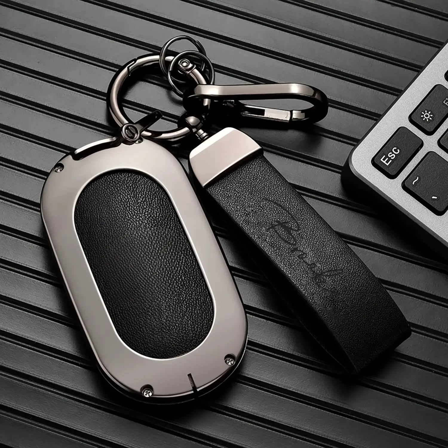 Silver and black key fob with a textured leather strap on a custom engraved leather keychain personalized gift.