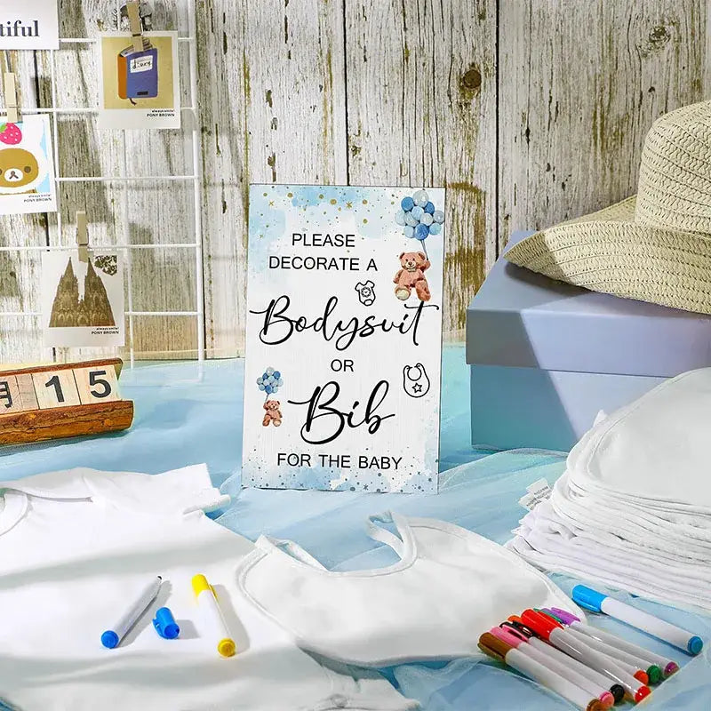a white baby bodysuit with soft smooth fabric and delicate shoulder straps included in a diy baby shower bib and bodysuit decorating kit