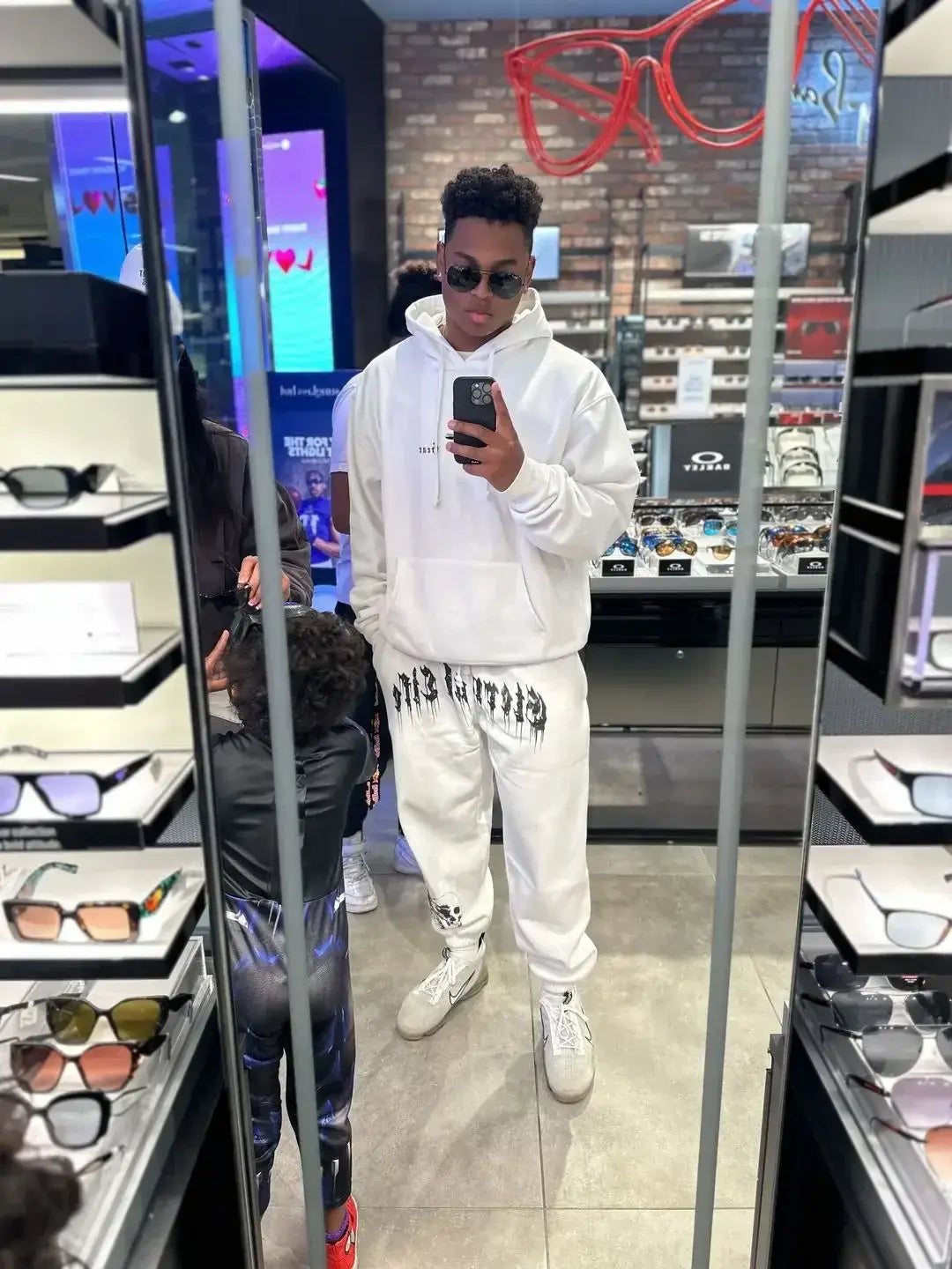 Hoodie blanc avec du texte graphique noir sur l’avant, conçu pour les hommes dans le cadre de vêtements d’entraînement pour sweatpants graphiques.