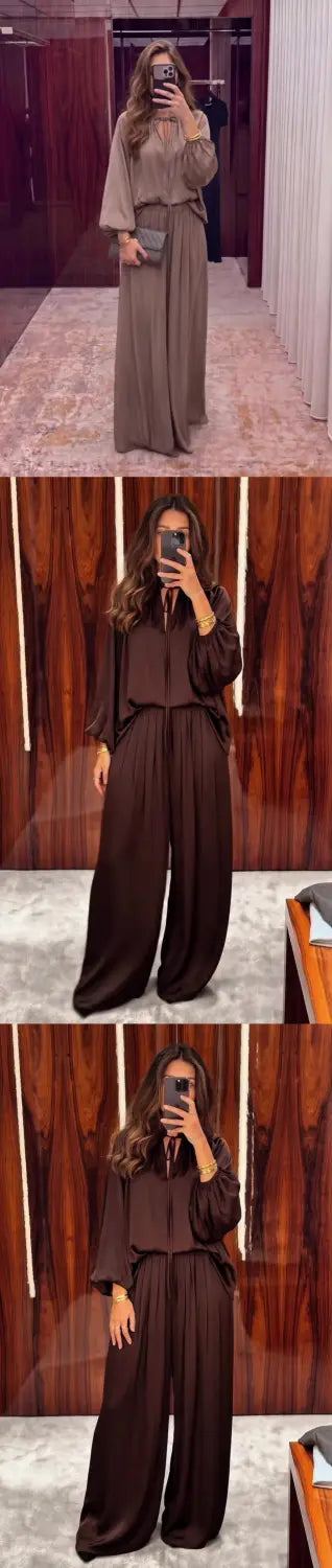 Eine Frau, die ein elegantes Satin-Set in passender Kombination für Frühling und Sommer trägt: ein zweiteiliger Jumpsuit in kräftigem Braun mit langen Ärmeln und Hosen mit weitem Bein.