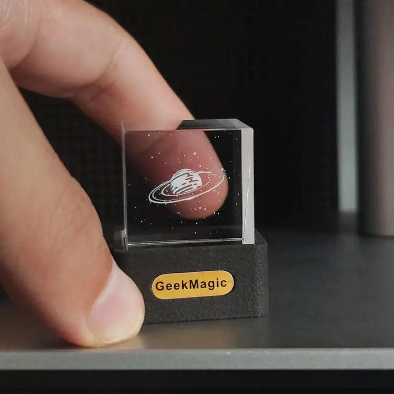 Geekmagic smart weather station crystal gif clock featuring a clear transparent cube with a laser-engraved Saturn design and starry background.