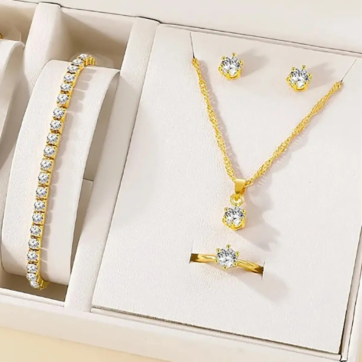 Juego de joyería de 5 piezas con circonitas cúbicas de color dorado con engaste de circonitas tipo diamante, que presenta un collar de cadena delicada con dije, aretes tipo botón a juego, una pulsera elegante y un anillo