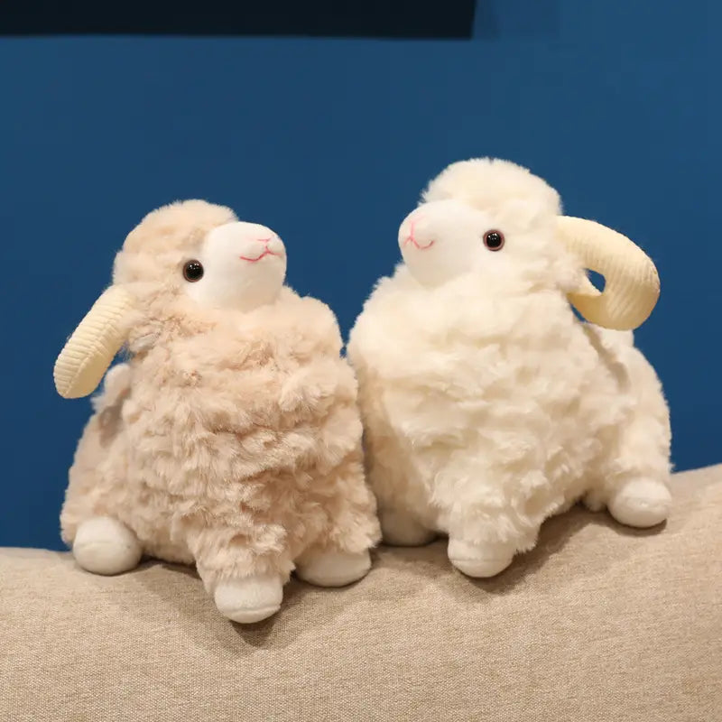 Zwei Plüschschaf-Geschmacktiere mit cremefarbenem und flauschigem weißem weichem, strukturiertem Wollfell, bestickten Details im Gesicht und geschwungenen Hörnern, entworfen als niedliche Kawaii-Weichpuppen.