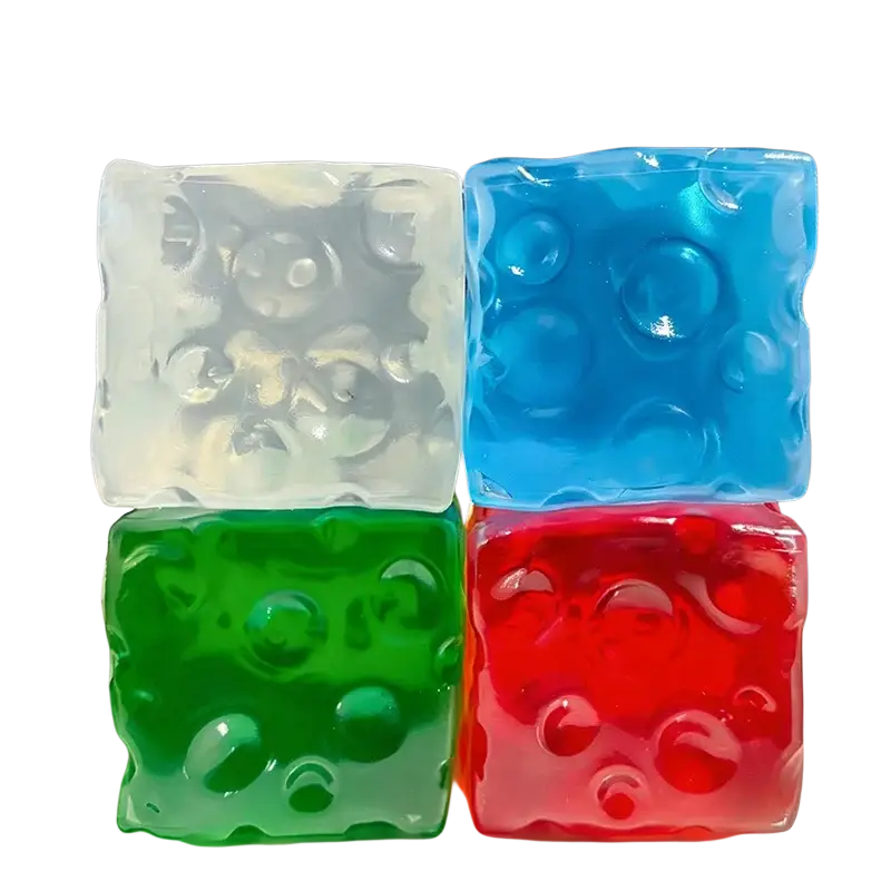 Vier transluzente, farbenfrohe Vaseline-Käse-Quetschwürfel aus weiß, blau, grün und rot mit strukturierter Oberfläche und eingebetteten Bläschen.