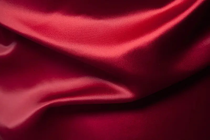 Stoff des Herrenhemds mit goldfarbenem Besatz aus Satin in edlem Crimsonsatin mit glatter, glänzender Oberfläche und fließenden Falten