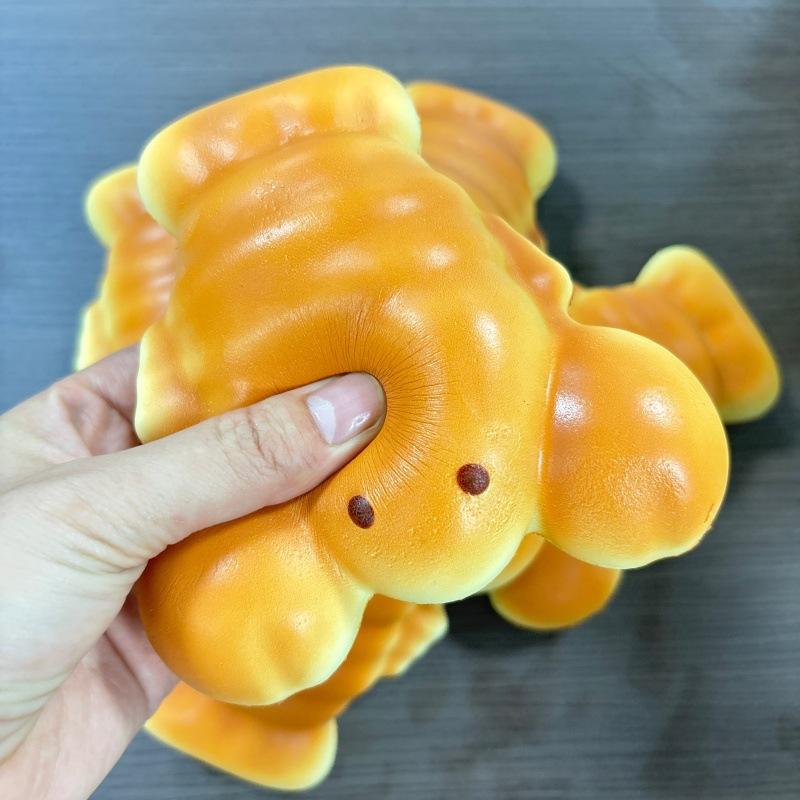 A soft orange goldfish-shaped slow rising toast fidget toy with small black dot eyes and a smooth glossy surface designed for daily stress relief.