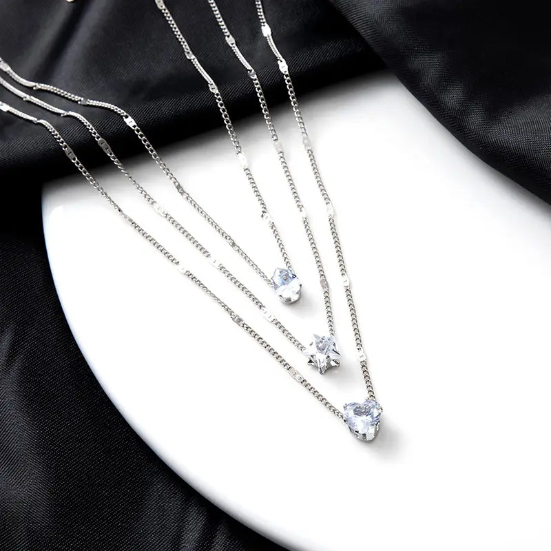 Three delicate silver chain zircon layered pendant necklaces for women each featuring a unique clear crystal pendant in different shapes.