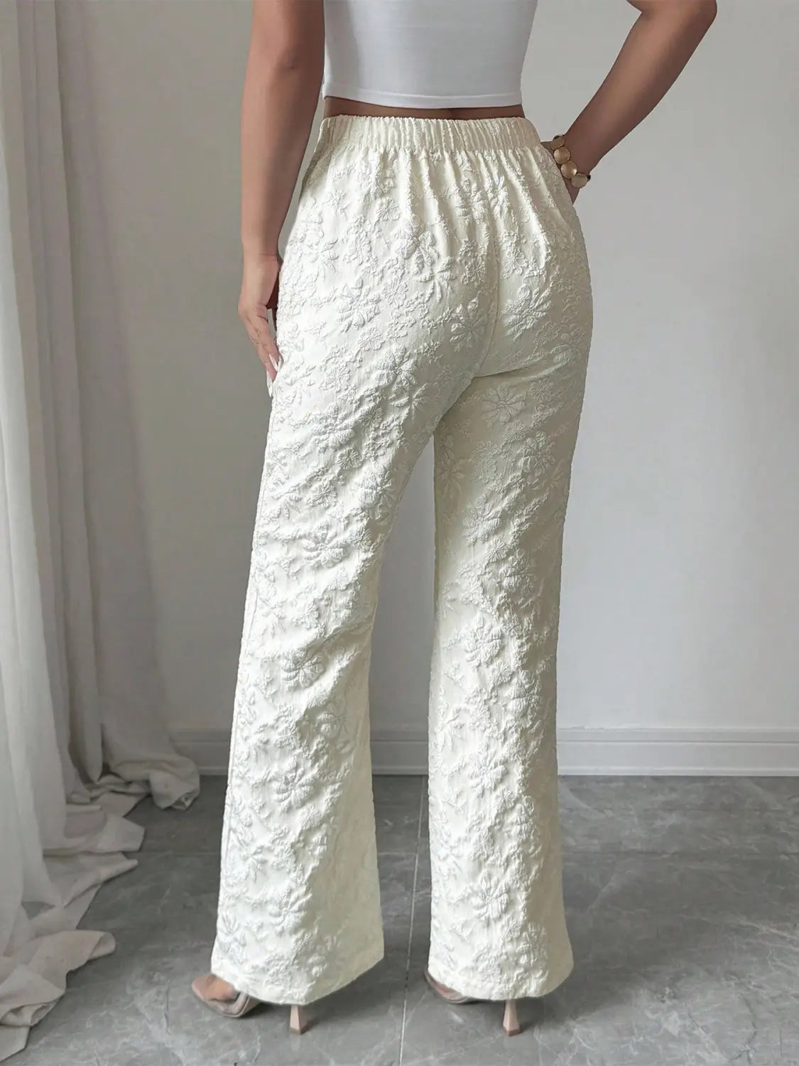 Cremefarbene weiße Spitzenhose mit hoher Taille und weitem Bein, mit elastischem Bund und aufwendiger floraler Stickerei.