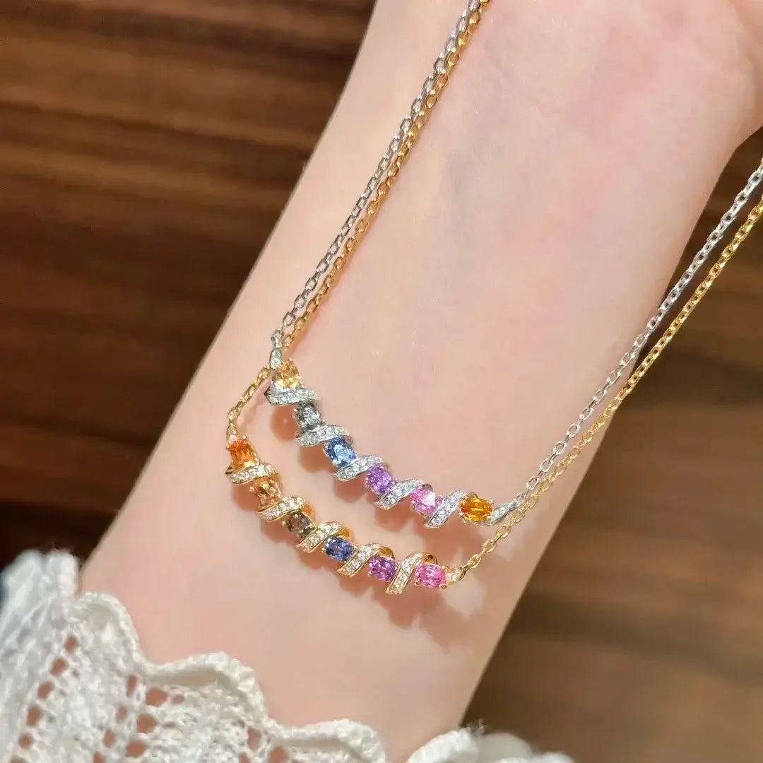 Un délicat collier en argent à double rangée au design tourbillonnant, présentant des pierres précieuses de couleur orange, bleue, violette et rose serties dans un métal ton or.
