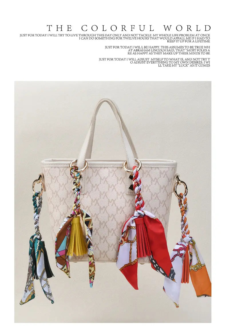 Un sac à main matelassé beige avec des anses assorties et des porte-clés à glands de foulard en soie fixés sur les côtés.