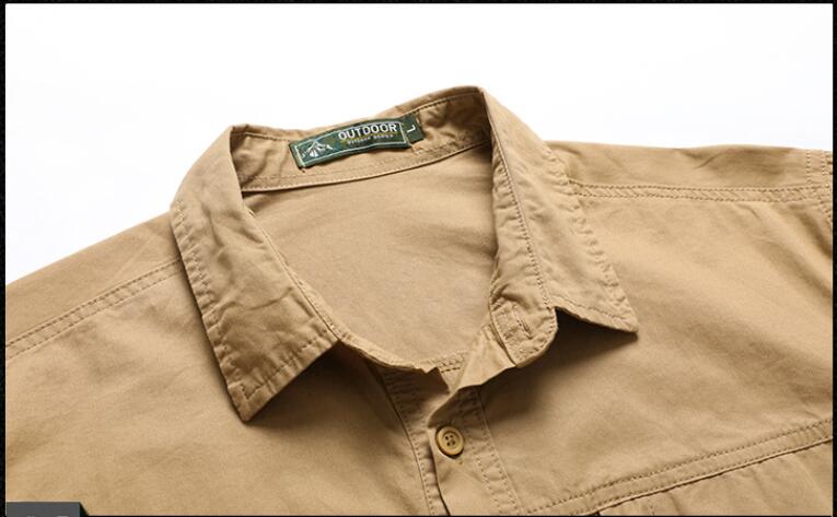 Herren-Workwear-Hemd ohne Falten aus beiger Baumwolle mit grünem Outdoor-Brand-Tag am Kragen, geeignet für die lässige Nutzung im japanischen Stil.
