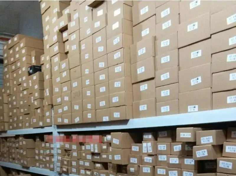 Stacks of brown cardboard boxes with white labels containing VW Passat door handle cover trim in carbon fiber.