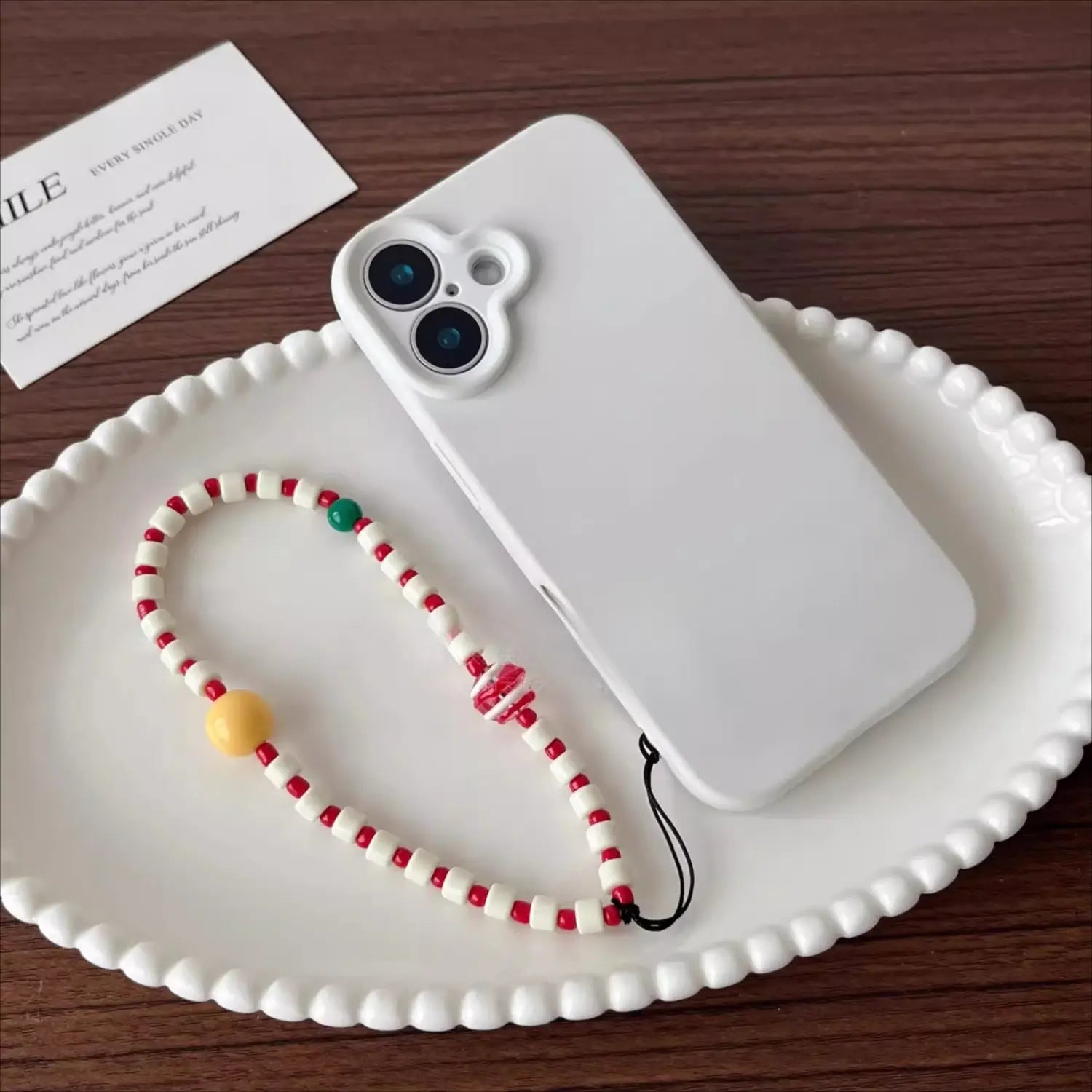 étui de téléphone blanc avec un bracelet de téléphone à perles colorées présentant des perles rouges et blanches, rehaussées par des perles jaunes et vertes