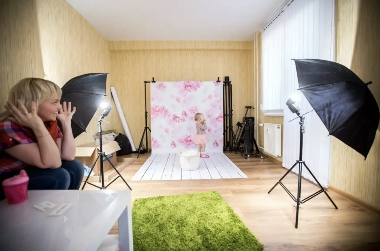 a baby seated in front of a pink floral-patterned studio backdrop for new year party photography featuring fireworks and a clock design